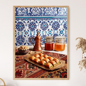 May include: A framed print featuring a still life with Middle Eastern food and decor. A copper coffee pot, jars of preserves, a tray of pastries, and a bowl of nuts are arranged on a patterned tablecloth against a blue and white tile background.