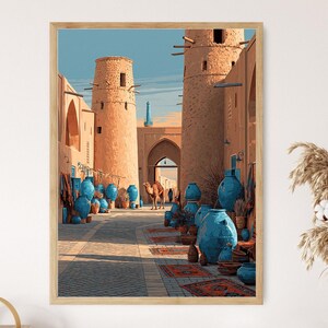 May include: A framed print of an illustration depicting an ancient Middle Eastern marketplace. The artwork features tan-colored buildings, blue pottery, and a camel walking down a cobblestone street. The sky is a clear blue.