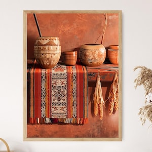 Può includere: Una stampa incorniciata con una natura morta con ceramiche in terracotta e un tessuto tessuto colorato. Le ceramiche includono un grande vaso con una cannuccia scura, un recipiente rotondo e piccole tazze. Il tessuto ha un motivo rosso, arancione e crema.
