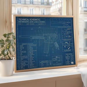 K&ouml;nnte beinhalten: Ein gerahmter Bauplan einer Ruger American Rifle mit detaillierten technischen Zeichnungen in Wei&szlig; auf blauem Hintergrund. Der Holzrahmen umgibt den Druck, der Text wie "Technical Schematic" und "Scale 1:1" enth&auml;lt. Eine Topfpflanze steht in der N&auml;he.
