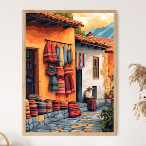 May include: A framed print of a colorful street scene. The artwork depicts buildings with orange walls and red tile roofs. Woven textiles in various colors hang from a rod. A person sits on a step in the shade. Colorful woven baskets are stacked.