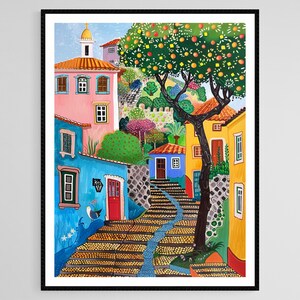 May include: Colorful art print of a European village scene. Buildings in shades of pink, blue, and yellow line a cobblestone street. A tree laden with orange fruit and a small church are visible in the background. The artwork is framed in black.