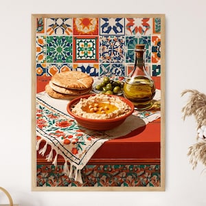 May include: A framed wall art print featuring a bowl of hummus topped with chickpeas, a stack of pita bread, a small dish of green olives, and a glass bottle of olive oil on a table covered with a floral patterned cloth against a tiled background.