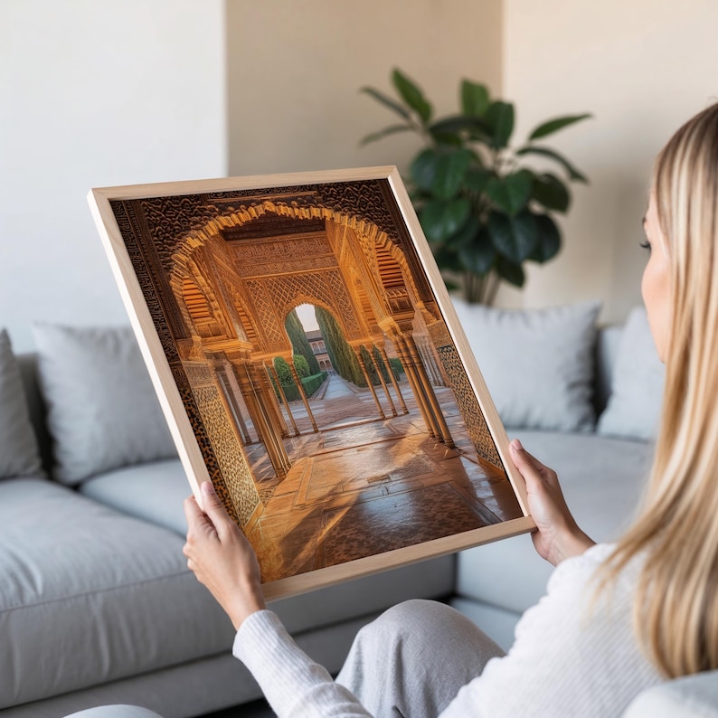 May include: A framed photograph of a grand, ornate archway with intricate details in a golden hue. The archway leads to a courtyard with lush greenery and a pathway.