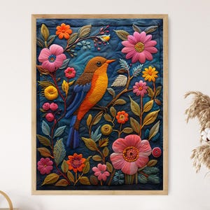 Puede incluir: Una obra de arte bordada colorida que presenta un pájaro con plumaje naranja y amarillo posado en una rama rodeado de flores vibrantes. La obra de arte está enmarcada en un marco de madera.