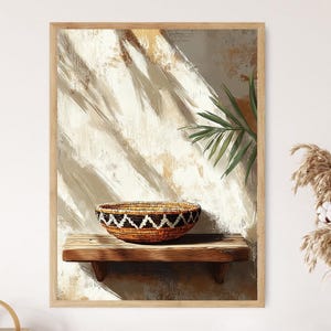 May include: A framed art print featuring a woven basket with a geometric design, resting on a wooden shelf. The background has a textured, neutral color palette with a hint of green foliage. The artwork evokes a sense of rustic elegance.