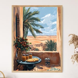 May include: A framed print depicting a desert scene viewed from a balcony. The artwork features a table with food and drinks, a palm tree, and a view of sand dunes and buildings under a blue sky. The frame is a light wood color.
