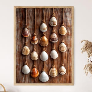 May include: A framed artwork featuring a collection of seashells suspended by knotted rope against a rustic wooden background. The shells vary in color, from white to brown, creating a coastal, nautical theme. The artwork is framed in a light wood.