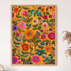 Peut inclure: Impression florale encadrée, avec des fleurs brodées aux couleurs orange, rose, violet et bleu sur un fond jaune doré. L'œuvre présente un motif botanique détaillé avec diverses fleurs et un feuillage vert. Le cadre est en bois.