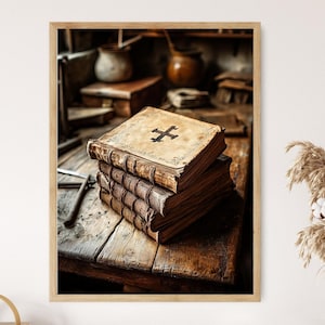 May include: A framed print featuring a stack of antique books with worn, brown covers. The top book displays a black cross symbol. The books rest on a rustic wooden table, with other aged objects in the background, creating a vintage aesthetic.