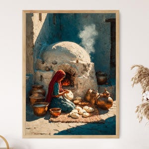 May include: A framed print depicts a woman in a red head covering and blue dress, baking bread near a stone oven. The scene is set outdoors with various copper pots and loaves of bread. The artwork has a warm, inviting color palette.