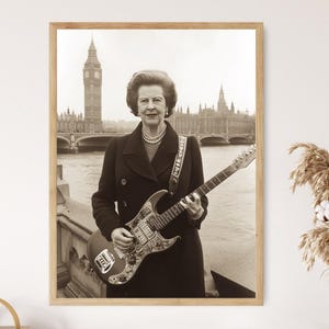 May include: A black and white photograph of a woman playing an electric guitar in front of the Houses of Parliament in London. The woman is wearing a black coat and a pearl necklace. The guitar is a dark colour with a white pickguard.