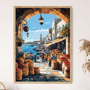 May include: A framed print of a vibrant marketplace scene. The artwork depicts a bustling outdoor market with people, boats, and buildings. The color palette includes shades of blue, orange, and brown, creating a warm and inviting atmosphere. The print is in a wooden frame.