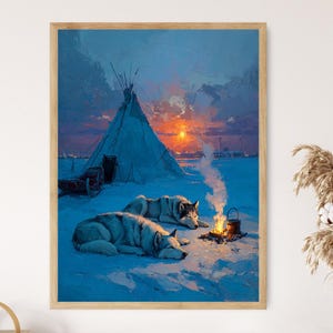 Op de afbeelding: Een ingelijste prent van een winterlandschap met twee wolven die in de sneeuw rusten bij een kampvuur. Een tipi en een zonsondergang zijn op de achtergrond te zien. Het kunstwerk is geschilderd in tinten blauw, oranje en wit.