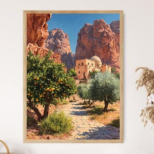 May include: Framed art print depicting a Middle Eastern landscape. The artwork features a stone path leading to a domed building, flanked by trees with oranges and olive trees. Towering red rock formations and a clear blue sky complete the scene.