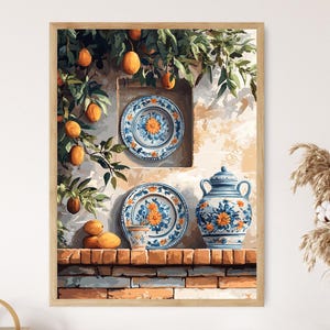 Può includere: Un dipinto ad acquerello incorniciato raffigura una scena rustica con piatti in ceramica, un vaso e una tazza, tutti decorati con motivi floreali blu e arancioni. L'opera d'arte include arance appese a un albero, su un muro strutturato e un davanzale in mattoni.