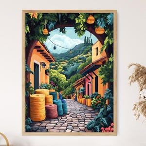 May include: A framed art print showing a vibrant street scene. The image features buildings with orange and pink walls, a cobbled street, and abundant greenery. The artwork is enclosed within a wooden frame.