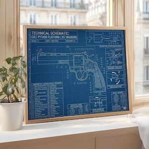 May include: A framed blueprint of a Colt Python Platform (.357 Magnum) firearm. The technical schematic is in white on a blue background, with detailed diagrams and text. The frame is light brown, and the image is set on a windowsill with a plant.