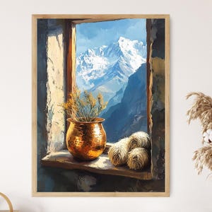 May include: A framed art print of a window overlooking a mountain range. A copper-colored pot with dried plants sits on the windowsill, with three balls of yarn. The sky is blue with snow-capped mountains.