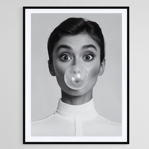 May include: A black and white portrait of a person blowing a bubble with their mouth. The person is wearing a white collared shirt and has their hair pulled back.