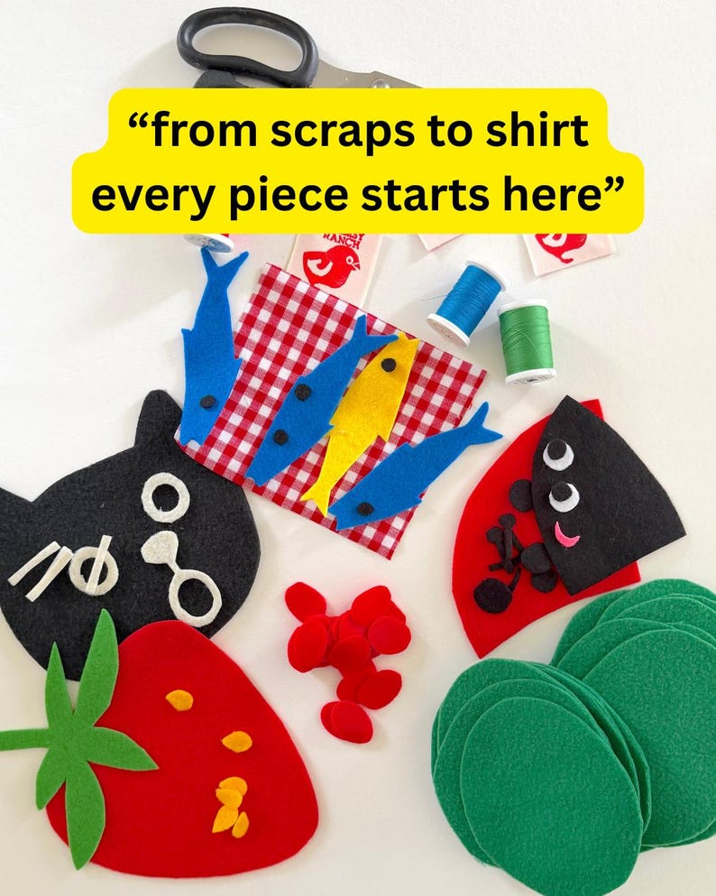 May include: A collection of felt craft pieces including a red strawberry, a black cat face, blue and yellow fish on a red gingham square, green circles, and red shapes. Includes spools of blue and green thread, scissors, and labels with text.