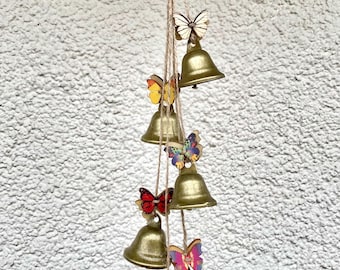 May include: A gold wind chime with six bells and six wooden butterflies in various colours. The butterflies are attached to the bells with twine.