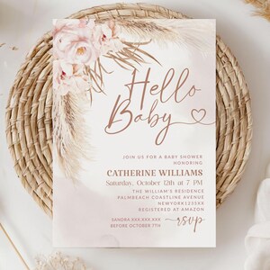 May include: A baby shower invitation with the words "Hello Baby" in a delicate script. The invitation features floral and pampas grass accents in soft pink and beige tones. Details include the honoree's name, date, time, and location.