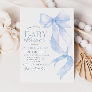 May include: A baby shower invitation with a light blue watercolor bow and ribbons. The invitation includes the text "BABY shower" and details for Catherine Williams' shower, including the date, time, and location.