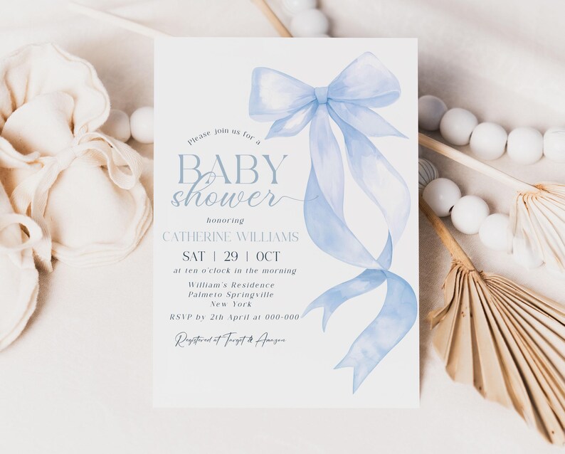May include: A baby shower invitation with a light blue watercolor bow and ribbons. The invitation includes the text "BABY shower" and details for Catherine Williams' shower, including the date, time, and location.