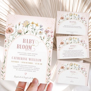 May include: A pink and gold baby shower invitation with floral illustrations. The invitation reads "Baby Bloom" and includes the date and time of the shower, the name of the mom-to-be, and the address. The invitation also includes a request for guests to bring nappies or books.