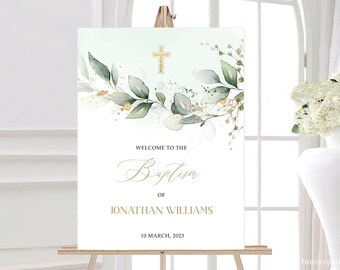 May include: A white welcome sign for a baptism, featuring a gold cross and watercolor greenery. The sign reads "Welcome to the Baptism of Jonathan Williams" and includes the date "10 March, 2023". The sign is displayed on a wooden easel.