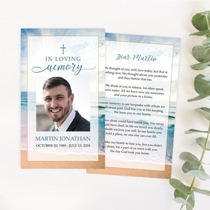 May include: A memorial card with a photo of a man and the text "In Loving Memory" and "Martin Jonathan, October 20, 1985 - July 13, 2018". The background is a blue sky with white clouds and a beach scene with waves.