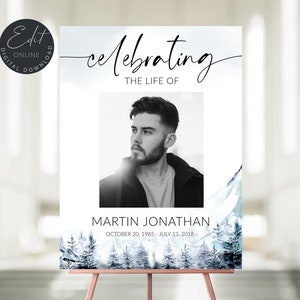 以下が含まれることがあります： 白地に男性の白黒写真が載っており、写真の真上に「人生を祝う」というテキストがあります。写真の真下には「Martin Jonathan」という名前と「1985年10月20日 - 2018年7月13日」という日付が書かれています。背景は雪山風景の水彩画です。