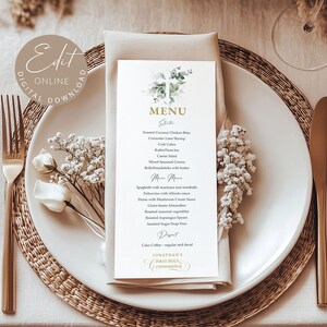 Könnte beinhalten: Eine elegante Tischdekoration mit einem weißen Teller, goldenem Besteck und einer Menükarte. Die Menükarte zeigt ein Blumendesign und den Text "MENU". Die Dekoration umfasst eine Serviette, Blumen und einen gewebten Tischset, wodurch eine elegante Atmosphäre entsteht.