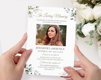 May include: A white memorial card with green foliage border. The card has a photo of a woman with long brown hair. The text reads "In Loving Memory" and includes the name "Jennifer Lawrence" with dates "October 20, 1985 - July 13, 2018". The card also includes details for a service and reception.