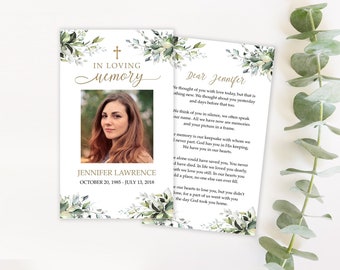 Op de afbeelding: Herdenkingskaart met foto van een vrouw, tekst "In Loving Memory", kruis en bloemmotieven. De naam Jennifer Lawrence en de data staan vermeld. Een tweede kaart bevat een brief.