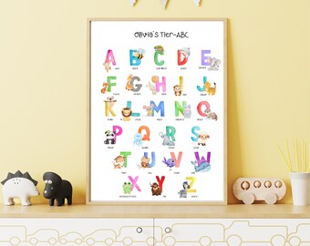 May include: A framed alphabet poster with the text "Olivia's Tier-ABC". Each letter is colorfully illustrated with an animal, such as a bee for B, a lion for L, and a zebra for Z. The poster is displayed on a white cabinet.