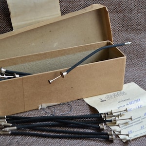 May include: A cardboard box with a lid open, revealing a set of black and silver tools. The tools are arranged in a row and are all the same length. The box is labeled with the text "ATTESTATI" and "N. 93/1967".
