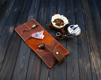 May include: A brown leather tobacco pouch with a pipe, tobacco, and a tin of "Peter Stokkebye -  Kurbina Tabak" tobacco.