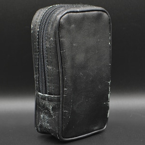 Könnte beinhalten: Ein rechteckiges schwarzes Lederetui mit Reißverschluss. Das Etui hat ein abgenutztes, abgenutztes Aussehen mit sichtbaren Gebrauchsspuren. Der Reißverschluss ist schwarz, und das Etui scheint leer zu sein.
