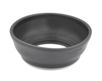 May include: A black, circular camera lens hood with a wide, tapered opening. The exterior surface features the embossed text HELIOPAN GERMANY. The interior of the hood has a series of concentric circular ridges designed for light management.