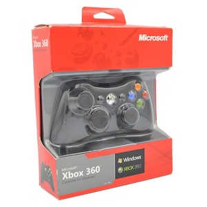 Può includere: Un controller Microsoft Xbox 360 nero per Windows nella sua confezione originale rossa e grigia. La scatola presenta il logo Microsoft, il marchio Xbox 360 e il logo Windows, con una finestra in plastica trasparente che mostra il controller.