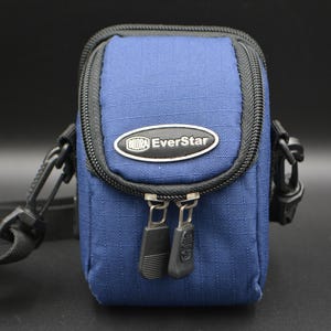 May include: A blue EverStar camera bag with a black zip and strap. The bag is rectangular with rounded edges and a black zip. The EverStar logo is on the front of the bag.