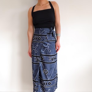 Könnte beinhalten: Ein schwarzes Neckholder-Top kombiniert mit einem Wickelrock. Der Rock ist dunkelblau mit einem weißen und schwarzen geometrischen Muster. Der Rock wird in der Taille gebunden. Das Outfit ist lässig und stilvoll.