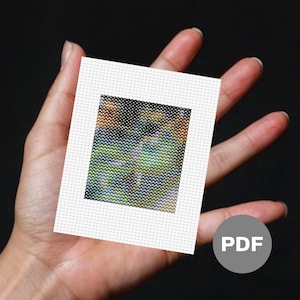 Puede incluir: Primer plano de un pequeño lienzo blanco con una imagen pixelada de colores de un paisaje. El lienzo está siendo sostenido por una mano. La palabra "PDF" está impresa en un círculo gris en la esquina inferior derecha de la imagen.