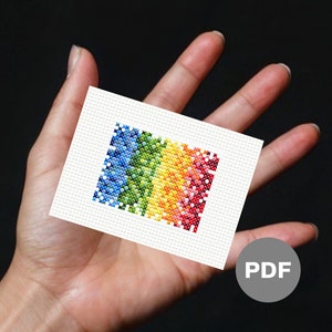 Könnte beinhalten: Ein kleiner, weißer Stoff mit einem Regenbogen-Kreuzstichmuster. Der Stoff wird in einer Hand gehalten. Das Wort "PDF" ist auf einem grauen Kreis in der unteren rechten Ecke des Bildes gedruckt.