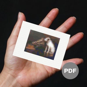 May include: A small, white, framed cross-stitch pattern featuring a dog and a cat sitting together. The cross-stitch is on a white background with a black border.
