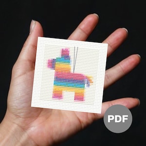 May include: A colorful cross-stitch pattern of a pinata shaped like a donkey. The pinata is decorated with rainbow stripes and has a string attached to the top.