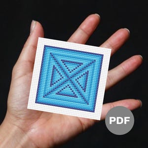 May include: A blue and white cross-stitch pattern with a geometric design. The pattern is framed in a white border and is on a white background. The pattern is available as a PDF download.