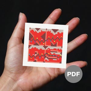 May include: A red and brown cross-stitch pattern with a Christmas theme. The pattern features a house with lights and a snowy roof.